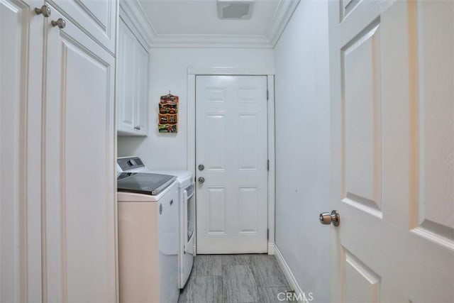 laundry area with washer and dryer, ornamental molding, and cabinets