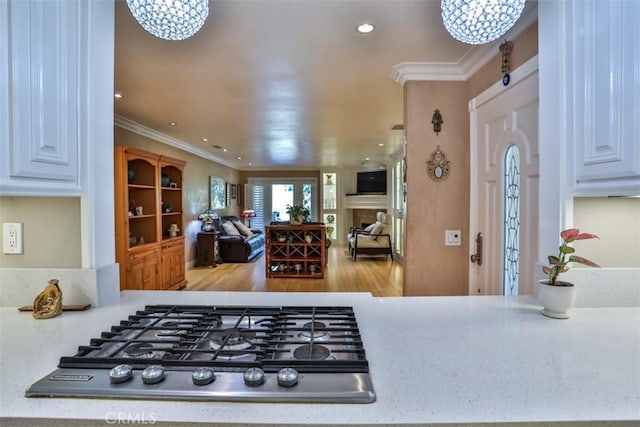 kitchen with stainless steel gas stovetop, crown molding, and an inviting chandelier