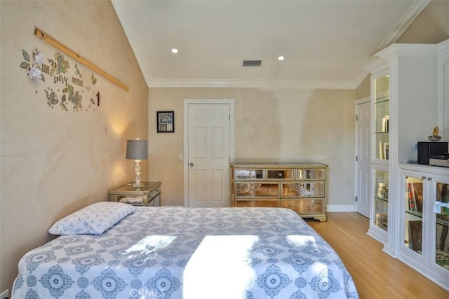 bedroom with light wood-type flooring, vaulted ceiling, a closet, and crown molding