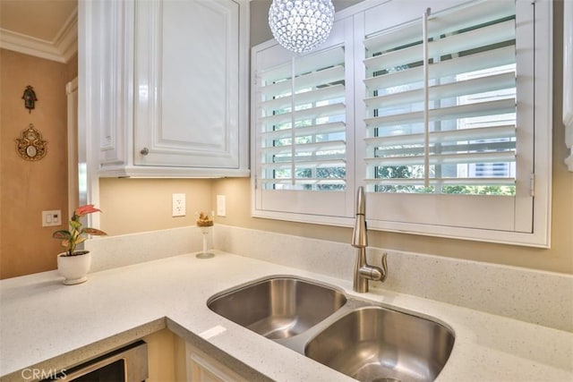 kitchen featuring dishwashing machine, sink, ornamental molding, white cabinets, and light stone counters