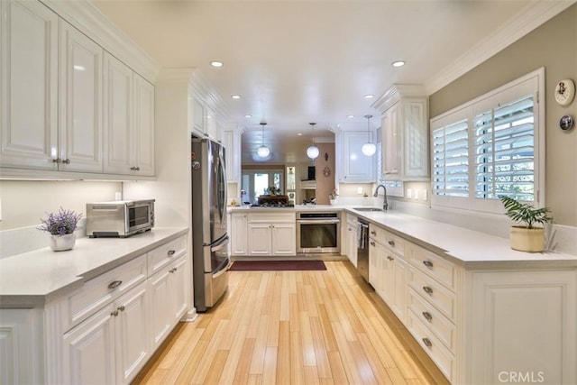 kitchen with kitchen peninsula, appliances with stainless steel finishes, pendant lighting, white cabinets, and sink