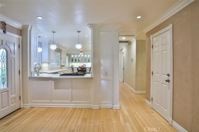 kitchen with pendant lighting, white cabinetry, sink, kitchen peninsula, and crown molding