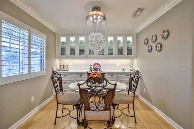 dining area featuring an inviting chandelier, crown molding, and light hardwood / wood-style flooring