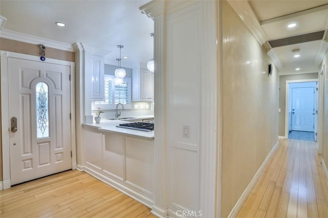 foyer with light hardwood / wood-style floors, sink, and crown molding