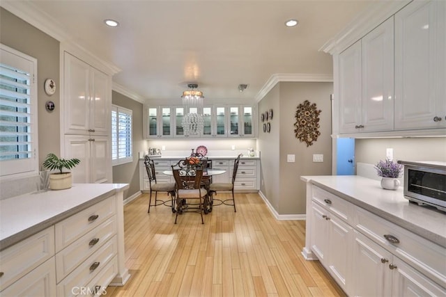 kitchen with ornamental molding, light hardwood / wood-style flooring, and white cabinets