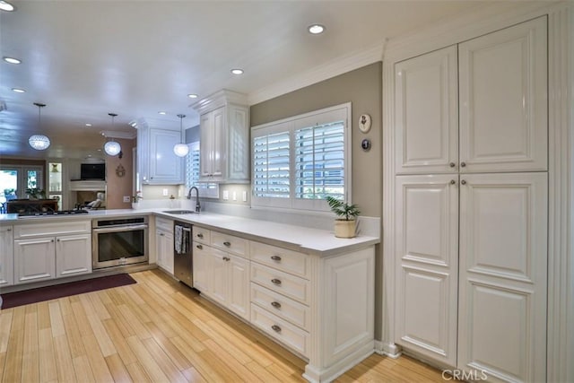 kitchen with kitchen peninsula, stainless steel appliances, decorative light fixtures, white cabinets, and sink