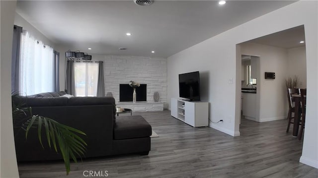 living room with hardwood / wood-style flooring, sink, and a stone fireplace