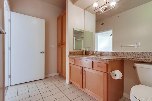 bathroom with toilet, vanity, and tile patterned floors