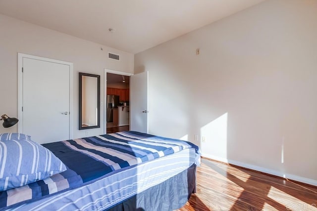 bedroom featuring hardwood / wood-style flooring and stainless steel fridge