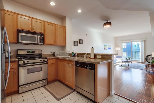 kitchen with kitchen peninsula, sink, light tile patterned flooring, stainless steel appliances, and dark stone counters