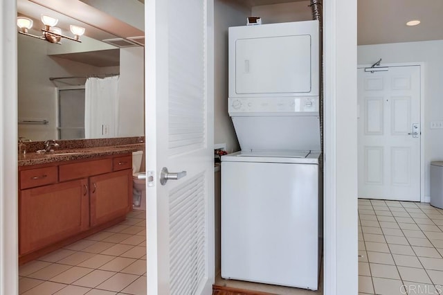 laundry room with stacked washer and dryer, light tile patterned flooring, and sink