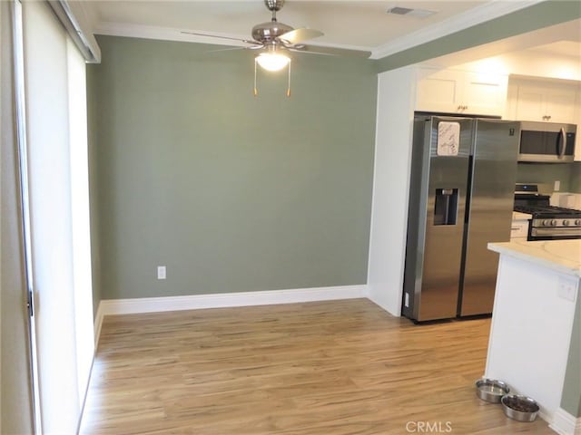 kitchen with white cabinetry, ceiling fan, appliances with stainless steel finishes, light wood-type flooring, and crown molding