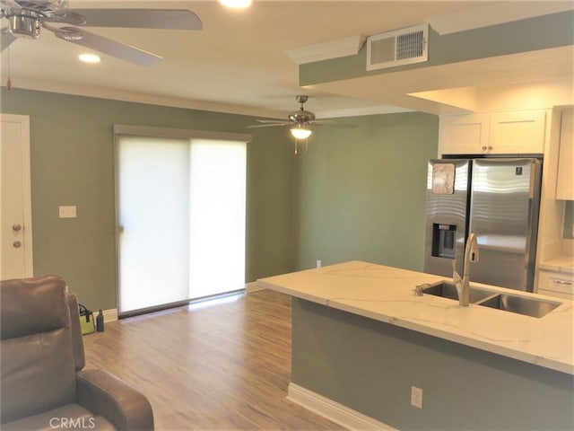 kitchen featuring white cabinetry, light hardwood / wood-style floors, stainless steel refrigerator with ice dispenser, light stone counters, and sink