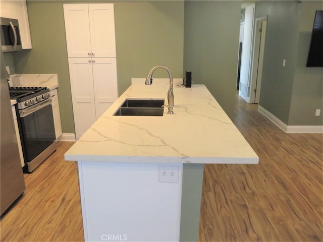 kitchen featuring appliances with stainless steel finishes, light stone countertops, white cabinetry, and sink