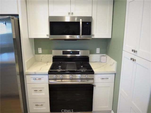 kitchen with light stone counters, white cabinets, and appliances with stainless steel finishes