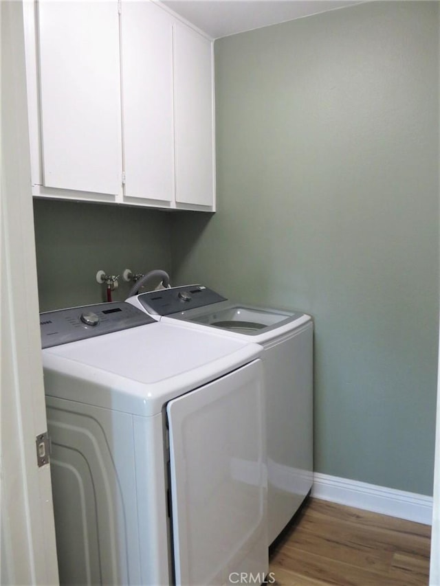 washroom featuring cabinets, separate washer and dryer, and wood-type flooring