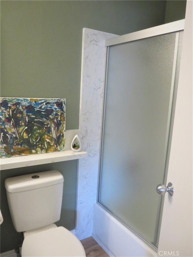 bathroom featuring toilet, enclosed tub / shower combo, and hardwood / wood-style floors