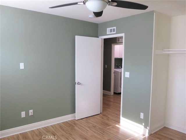 unfurnished bedroom with ceiling fan, washer / clothes dryer, and light hardwood / wood-style floors