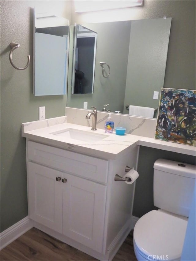 bathroom with toilet, vanity, and hardwood / wood-style flooring