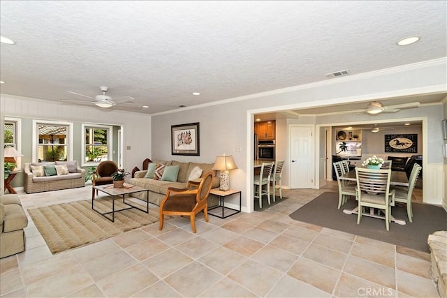 living room with ceiling fan, a textured ceiling, and ornamental molding