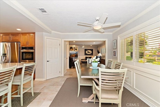 dining room featuring ceiling fan, light tile patterned floors, and crown molding