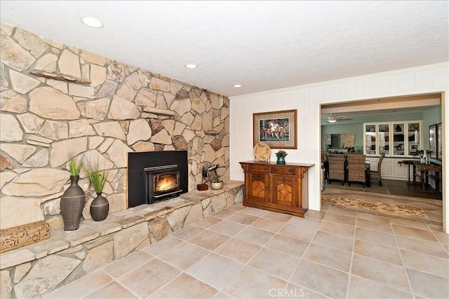 living room featuring a textured ceiling, ceiling fan, crown molding, and a wood stove