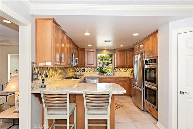 kitchen with backsplash, a breakfast bar, kitchen peninsula, light tile patterned flooring, and stainless steel appliances