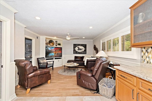 living room with light wood-type flooring, ceiling fan, and ornamental molding