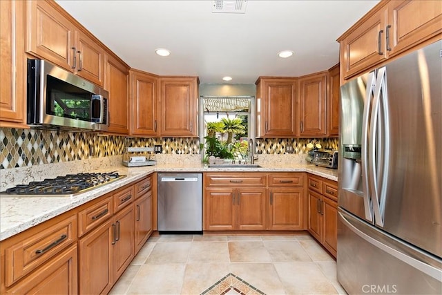 kitchen featuring light stone countertops, sink, stainless steel appliances, and tasteful backsplash