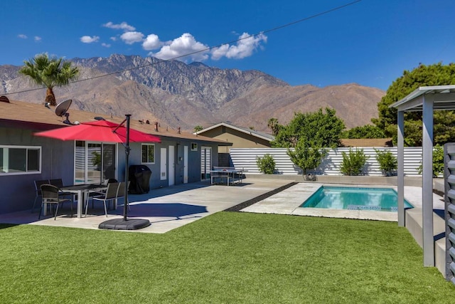 view of pool featuring grilling area, a patio area, a mountain view, and a yard