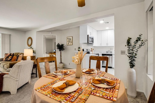 carpeted dining room with ceiling fan