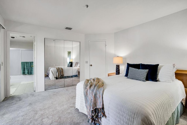 bedroom featuring ensuite bathroom, a closet, and light carpet