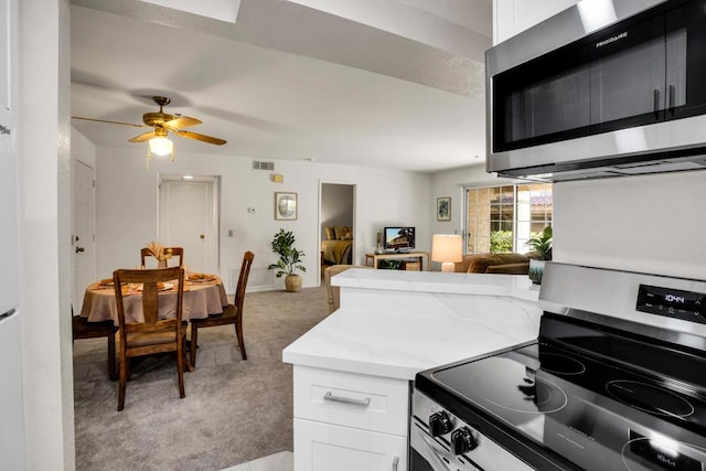 kitchen featuring light stone counters, light colored carpet, white cabinetry, and appliances with stainless steel finishes