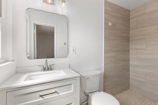 bathroom featuring toilet, vanity, and a tile shower