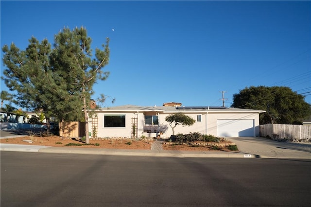 ranch-style home featuring a garage and solar panels