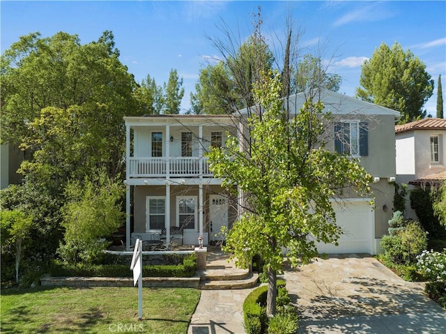 view of front of property with a garage, a front lawn, a balcony, and a porch