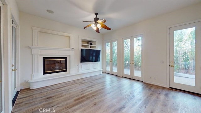 unfurnished living room with ceiling fan, plenty of natural light, light hardwood / wood-style floors, and built in features