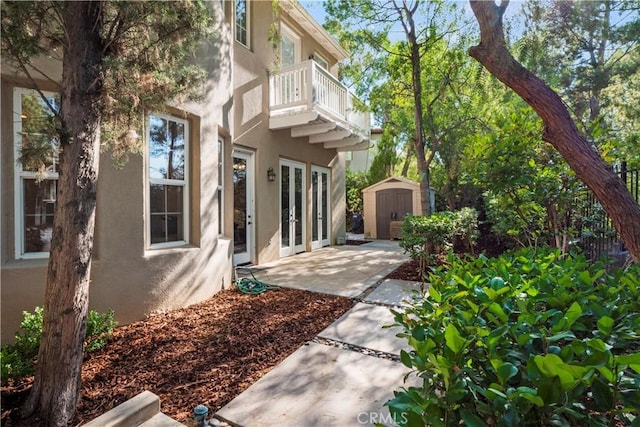 exterior space featuring a shed, a patio, a balcony, and french doors