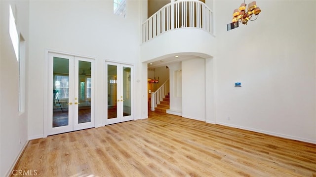 empty room with light hardwood / wood-style floors, french doors, and a chandelier