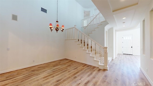 staircase featuring a towering ceiling, hardwood / wood-style floors, and a notable chandelier