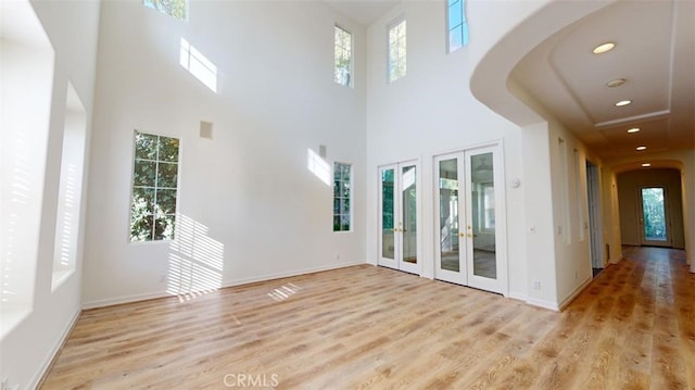 unfurnished living room featuring a wealth of natural light, french doors, and light wood-type flooring