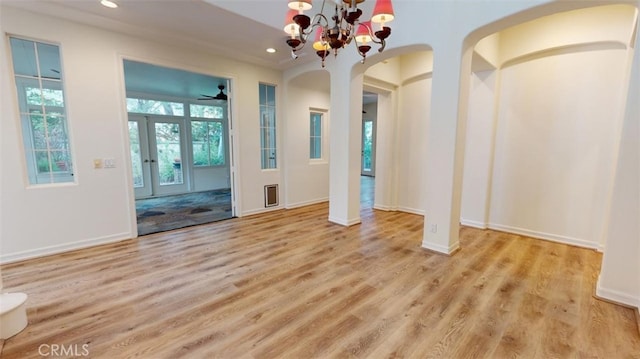 empty room featuring french doors, a chandelier, and light hardwood / wood-style flooring