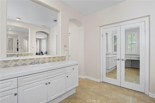 bathroom featuring tile patterned flooring, vanity, decorative backsplash, and french doors