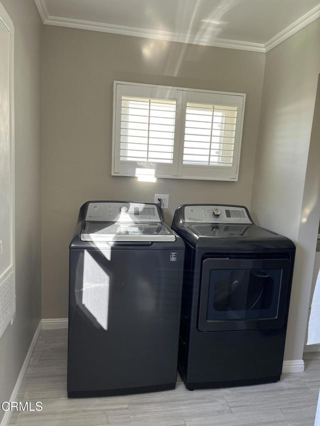 clothes washing area featuring washer and dryer and ornamental molding