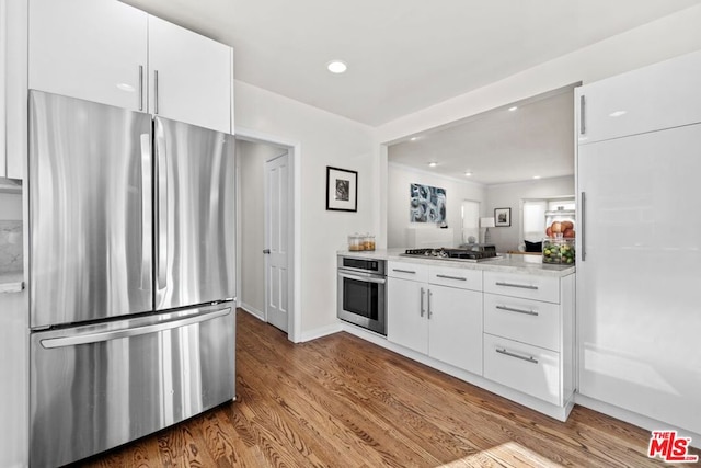 kitchen with stainless steel appliances, light hardwood / wood-style floors, and white cabinets