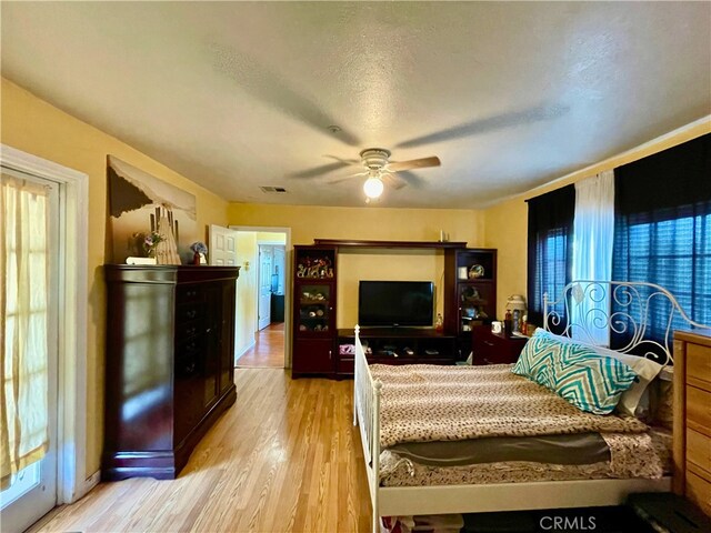 bedroom with ceiling fan, a textured ceiling, and light wood-type flooring