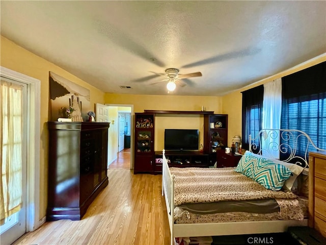 bedroom featuring ceiling fan, light hardwood / wood-style flooring, and a textured ceiling