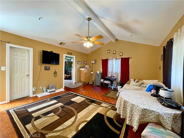 bedroom with parquet floors, ceiling fan, a walk in closet, and vaulted ceiling with beams