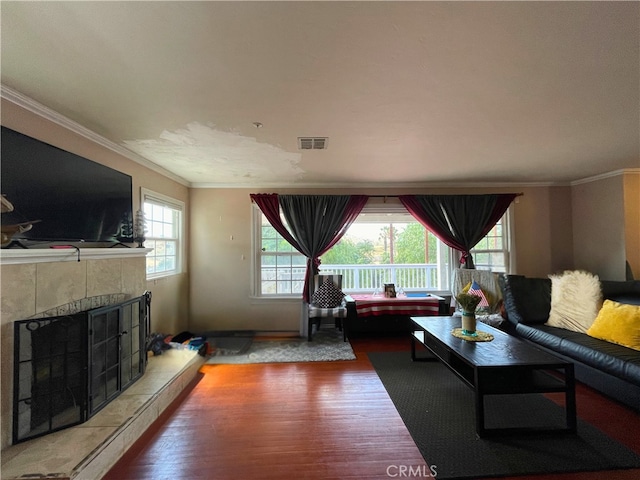 living room featuring crown molding, wood-type flooring, and a tile fireplace