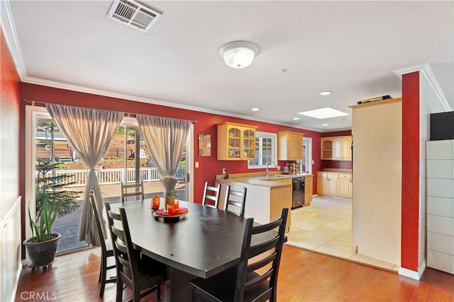 dining room with ornamental molding, sink, light hardwood / wood-style floors, and a skylight